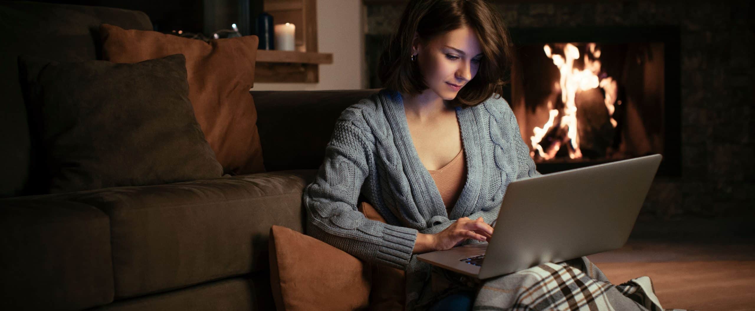 woman on laptop in home with fireplace